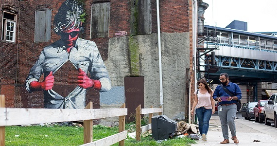 Alexis Roth walks by a mural in Philadelphia's Kensington neighborhood